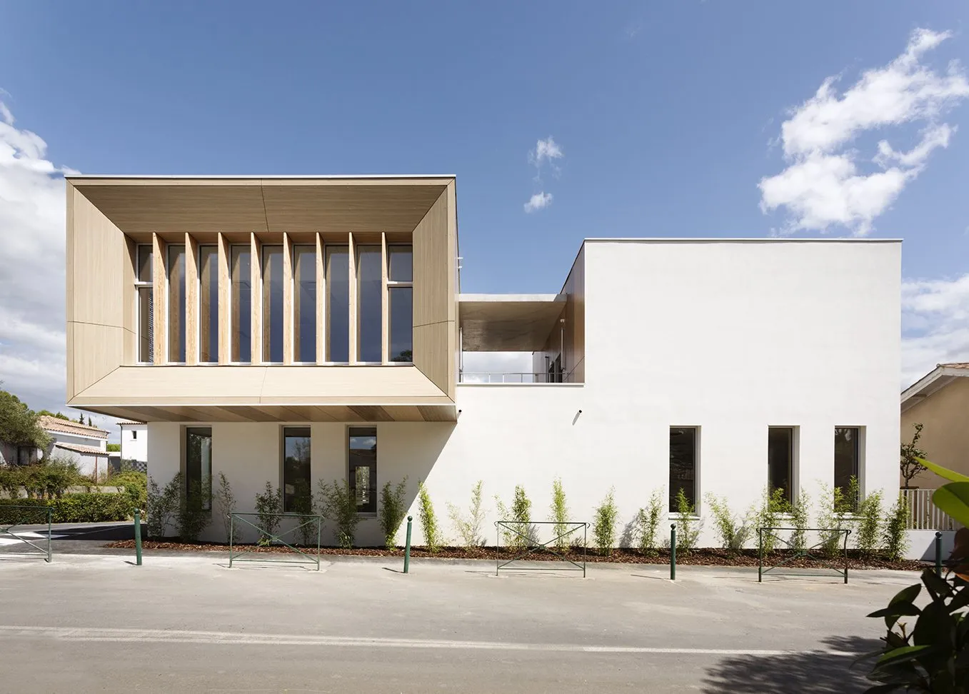 Façade d'école à lames de bois verticales devant la baie, Saint-Drézéry